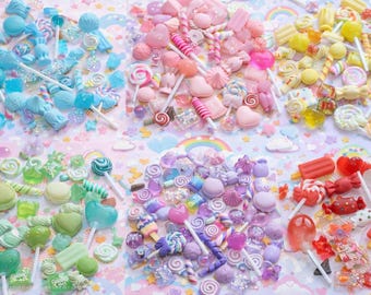 May include: A colorful assortment of candies, including lollipops, gummy bears, and hard candies, in shades of blue, pink, yellow, green, purple, and red. The candies are arranged on a pastel background with rainbows and clouds.