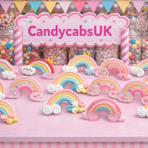 Puede incluir: Decoraciones en forma de arcoíris en colores pastel, rosa, amarillo, azul y blanco. Las decoraciones están dispuestas sobre una superficie rosa, con el texto "CandycabsUK" al fondo.