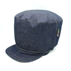 Op de afbeelding: Een blauwe denim pet met een platte bovenkant en een gebogen rand. De pet heeft een klein label aan de zijkant met de tekst "Hatafaya".