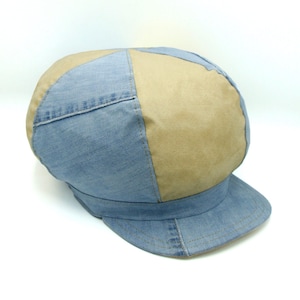 Op de afbeelding: Een blauwe en bruine denim newsboy-pet met een ronde kroon en een platte klep.