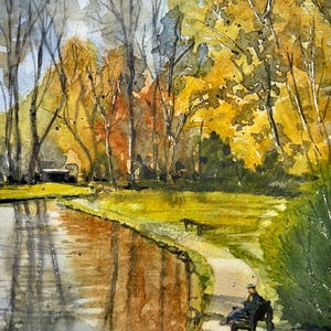 Puede incluir: Pintura a la acuarela de una escena de parque con un estanque que refleja árboles. La obra presenta a una persona sentada en un banco, rodeada de árboles con hojas amarillas y naranjas. La firma del artista, R. Coldwell, está en la esquina inferior izquierda.