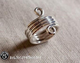Könnte beinhalten: Ein silberner Ring mit einem einzigartigen, gedrehten Design. Der Ring besteht aus mehreren Drähten, die miteinander verdreht sind, um einen Spiraleffekt zu erzeugen. Der Ring hat ein schlichtes, elegantes Design, das ein tolles Geschenk für jeden Anlass wäre.