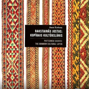 Pode incluir: Uma capa de livro com um título em letão, "Rakstainas jostas: kopigais kulturslanis", que se traduz como "Cintas estampadas: a camada cultural comum". A capa apresenta quatro cintas tecidas coloridas com padrões geométricos intrincados.