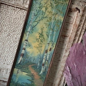 Peut inclure: Une peinture encadr&eacute;e repr&eacute;sentant une sc&egrave;ne de for&ecirc;t avec trois bouleaux et un chemin menant &agrave; un petit &eacute;tang. La peinture est r&eacute;alis&eacute;e dans un style aquarelle avec des nuances de vert, de bleu et de jaune.