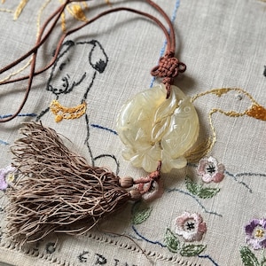 May include: A white ceramic mug with a black handle and the text "But First, Coffee" in a bold, black font. The mug is set against a blurred background, suggesting a cozy setting.