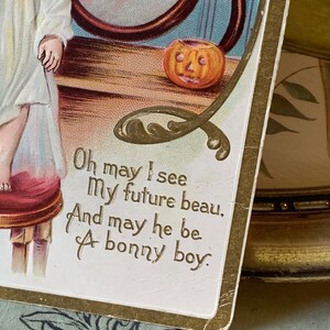 Pode incluir: Postal de Halloween vintage com borda dourada e o texto "Oh may I see My future beau, And may he be A bonny boy." A imagem apresenta uma ab&oacute;bora esculpida e uma crian&ccedil;a.