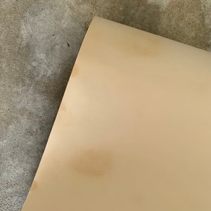 May include: A close-up of a light beige surface with three brown stains.