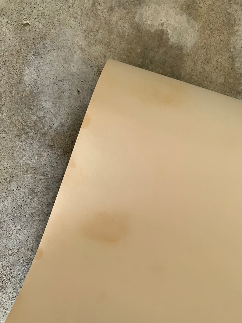 May include: A close-up of a light beige surface with three brown stains.