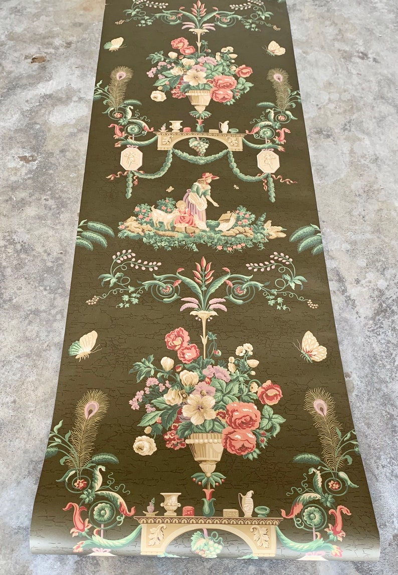 May include: Vintage wallpaper roll featuring a repeating pattern of floral bouquets, a woman tending to a goat, and ornate details. The wallpaper is on a dark green background with a textured finish.