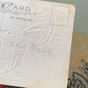 Pode incluir: Postal vintage com design floral em relevo e a palavra "CARD" no topo. O texto "FOR ADDRESS ONLY" est&aacute; impresso abaixo. Escrita manuscrita e texto em relevo vis&iacute;veis no cart&atilde;o. O postal &eacute; branco sujo.