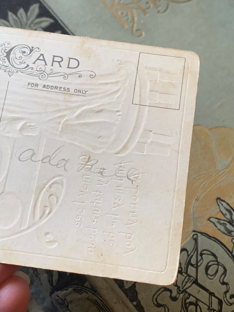 Pode incluir: Postal vintage com design floral em relevo e a palavra "CARD" no topo. O texto "FOR ADDRESS ONLY" est&aacute; impresso abaixo. Escrita manuscrita e texto em relevo vis&iacute;veis no cart&atilde;o. O postal &eacute; branco sujo.