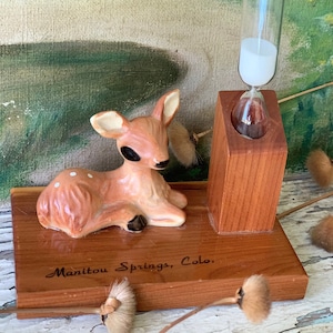 May include: A wooden hourglass with a ceramic deer figurine on a base that reads "Manitou Springs, Colo."