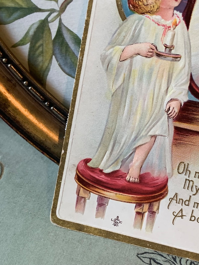 Pode incluir: Postal vintage com uma crian&ccedil;a em camisola branca segurando uma vela. A crian&ccedil;a est&aacute; em p&eacute; em um pequeno banquinho vermelho. O postal tem uma borda dourada, com o texto "Oh my..." vis&iacute;vel.