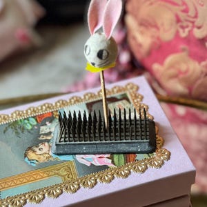 May include: A white ceramic mug with a black handle and the text "But First, Coffee" in a handwritten style. The mug is on a white surface. The mug is approximately 4 inches tall.