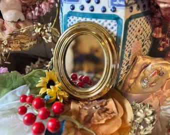 Petit miroir ovale vintage avec cadre en plastique doré suspendu au mur