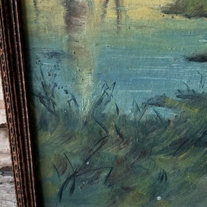 Peut inclure: Une peinture encadr&eacute;e repr&eacute;sentant une sc&egrave;ne de paysage avec une rivi&egrave;re et des arbres. La peinture est r&eacute;alis&eacute;e dans une palette de couleurs douces, des verts, des bleus et des jaunes. Les coups de pinceau sont visibles et donnent &agrave; la peinture un aspect textur&eacute;.