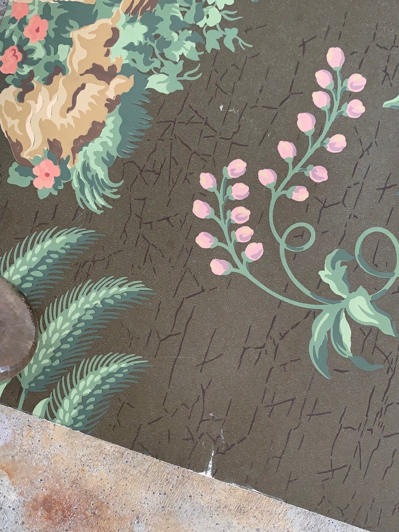 May include: A vintage wallpaper with a floral pattern. The wallpaper features pink flowers, green leaves, and a brown background. The wallpaper is cracked and worn, giving it a vintage look.
