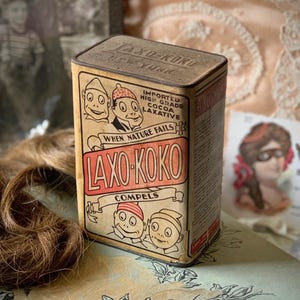 May include: Vintage tin box for Laxo-Koko cocoa laxative. The box is brown with red and white lettering. It features illustrations of cartoon characters and the text "When Nature Fails, Laxo-Koko Compels".
