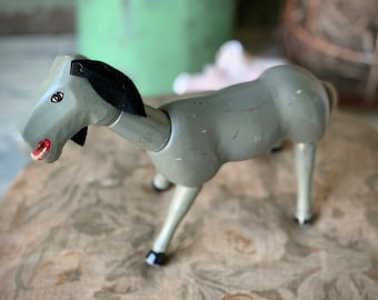 May include: A gray wooden toy horse with black painted hooves and a black mane. The horse has a painted red mouth and a white eye.