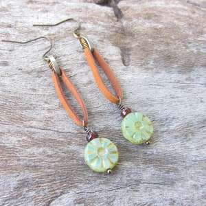 May include: A pair of dangle earrings with brown leather straps and green and white floral beads.