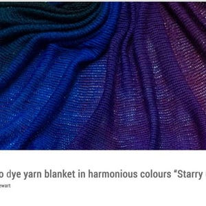 May include: Close-up of a textured blanket with a colour gradient. The blanket transitions from dark blue to bright blue and then to purple. The fabric has a subtle, shimmering effect, creating a starry galaxy appearance.