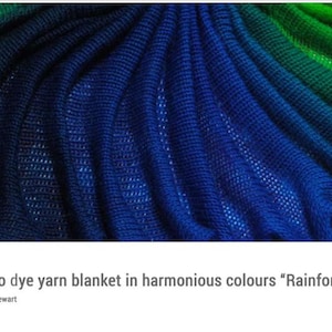May include: A knitted blanket in shades of blue and green, with a gradient effect. The blanket has a textured appearance, with visible stitches and a soft, flowing drape. The colour transitions from deep blue to vibrant green.