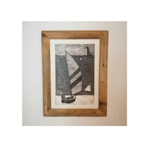 May include: A framed black and white print of a sailboat with striped sails on a body of water. The print is in a rustic wooden frame.