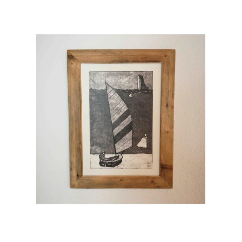 May include: A framed black and white print of a sailboat with striped sails on a body of water. The print is in a rustic wooden frame.