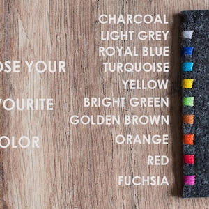 Peut inclure: Une pochette en feutre gris anthracite fonc&eacute; avec une rang&eacute;e verticale de fils color&eacute;s. Le texte indique : CHOOSE YOUR FAVOURITE COLOR, suivi d'une liste de couleurs : CHARCOAL, LIGHT GREY, ROYAL BLUE, TURQUOISE, YELLOW, BRIGHT GREEN, GOLDEN BROWN, ORANGE, RED, FUCHSIA.