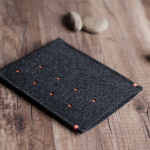 May include: A dark gray felt case with orange stitching. The case has a series of small holes throughout the surface.