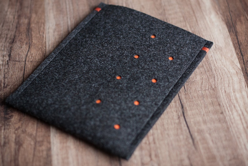 May include: A gray felt laptop sleeve with orange stitching and a pattern of evenly spaced holes.