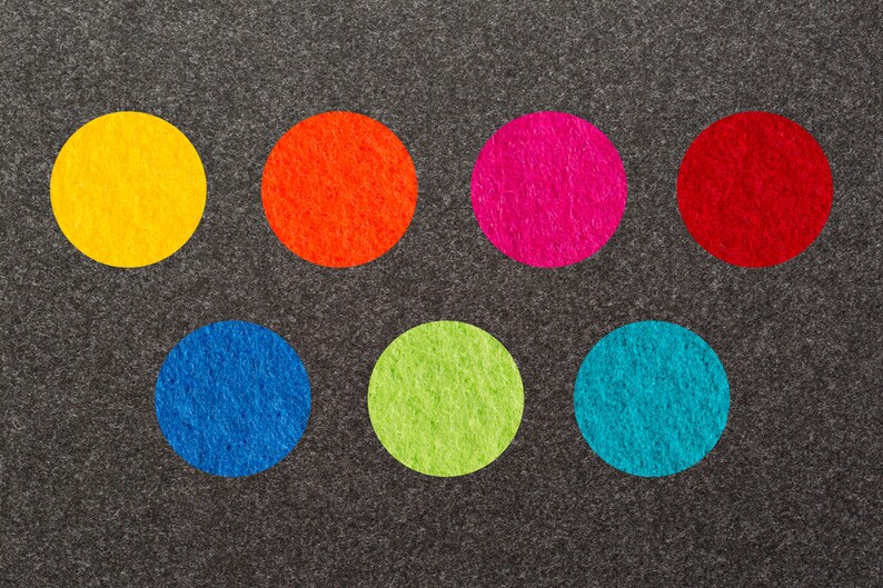 May include: Seven felt circles in different colors on a gray background. The colors are yellow, orange, pink, red, blue, green, and turquoise.