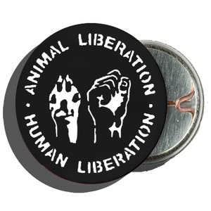 May include: Black and white button with the text "Animal Liberation - Human Liberation" in a circle around a raised fist and a paw print.