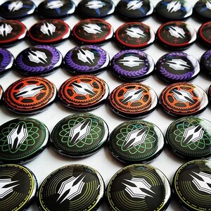 May include: A collection of round, colorful buttons with a variety of designs featuring a stylized, abstract logo. The buttons are arranged in rows on a white surface.