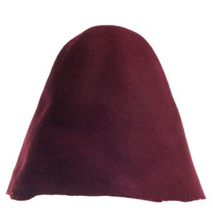 May include: A burgundy cloche hat. The hat is made of a soft, felt-like material. The hat has a rounded crown and a close-fitting brim. This hat is a stylish accessory.