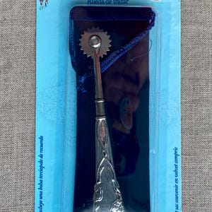 May include: A silver tracing wheel with a decorative handle, packaged in a blue and clear plastic sleeve. The package includes a blue velvet pouch. Text on the package reads "Tracing Wheel" and "Elizabeth's Vintage Notions".