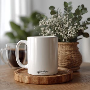 The back of a white coffee mug sitting on top of a wooden table with a small Moon Whisper Co logo on it.
