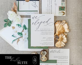 May include: Wedding invitation suite with green and black accents. The invitation features a watercolor floral design with white flowers and green leaves. The text reads "we eloped" and includes the couple's names, wedding date, and location. The invitation is accompanied by a green and black envelope, a gold leaf, and a ring box.