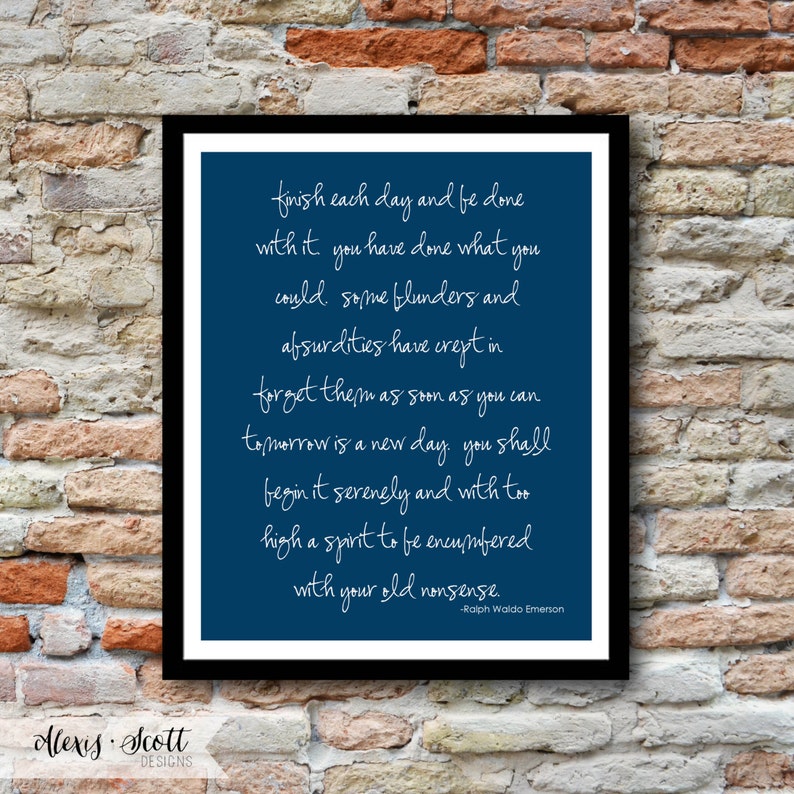 May include: A framed print with a navy blue background and white script. The text reads, "finish each day and be done with it..." and is signed "-Ralph Waldo Emerson." The frame is black, and the background is a brick wall.