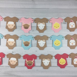 May include: A farm animal themed baby shower banner with alternating pink, blue, and brown onesies with different animal faces. The animals include a pig, lamb, bull, chick, and horse.