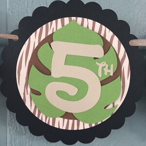 May include: A black and white zebra patterned circle with a green leaf shape containing a white number 5 and the word "th" in smaller font. The circle has a scalloped edge.