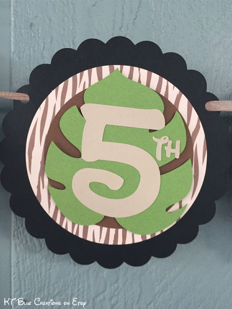 May include: A black and white zebra patterned circle with a green leaf shape containing a white number 5 and the word "th" in smaller font. The circle has a scalloped edge.
