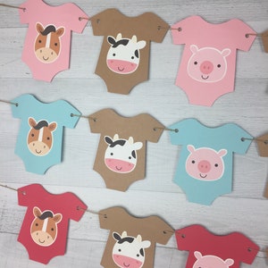 May include: A banner with nine baby onesies featuring farm animal faces. The onesies are in pink, blue, brown, and red. The animals are a horse, a cow, and a pig.