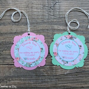 May include: Two pink and green thank you tags with a teacup and teapot design. The text on the tags reads "Thank You for making my party TEA-rified! Kenadic".