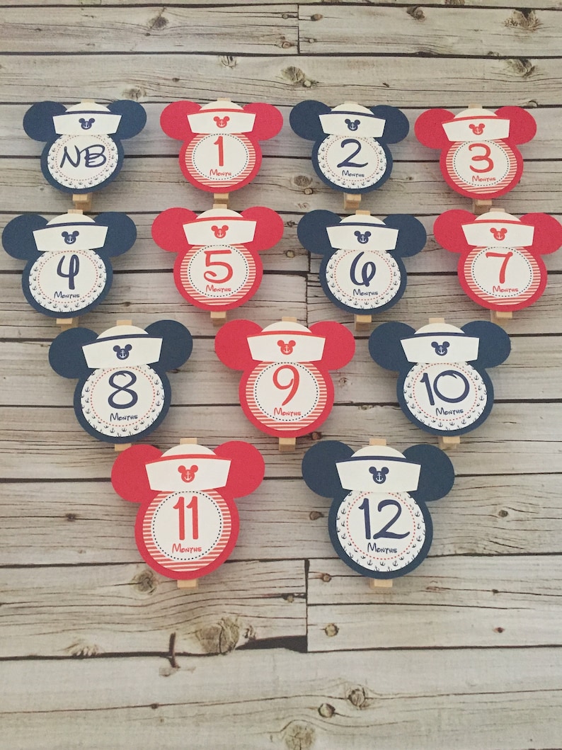 May include: Twelve red and blue Mickey Mouse-themed monthly milestone cards with white numbers and the word "Months" printed on each card. The cards are decorated with white anchors and red and white stripes.
