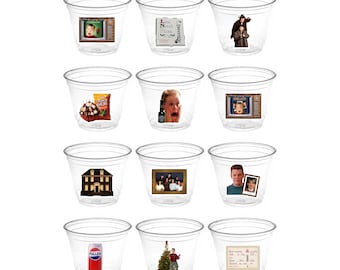 May include: A set of twelve clear plastic shot glasses, each with a different image from the movie "Home Alone." The images include scenes, characters, and props from the film, such as the house and Kevin.