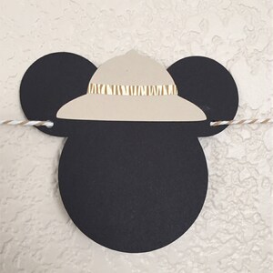 Puede incluir: Orejas de Mickey Mouse negras y blancas con un sombrero safari de color marr&oacute;n claro en la parte superior. El sombrero tiene una banda de rayas marrones y blancas.