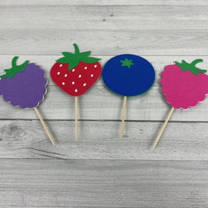 Peut inclure: Quatre d&eacute;corations de cupcakes en feutre de fruits color&eacute;s&nbsp;: une fraise rouge, une m&ucirc;re violette, une framboise rose et une myrtille bleue.