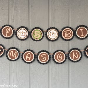 May include: A brown and tan banner with the words "Happy Birthday Mason" in black letters. The banner is decorated with images of Mickey Mouse and safari animals.