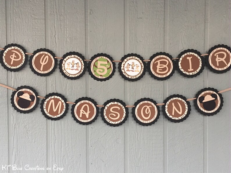 May include: A brown and tan banner with the words "Happy Birthday Mason" in black letters. The banner is decorated with images of Mickey Mouse and safari animals.
